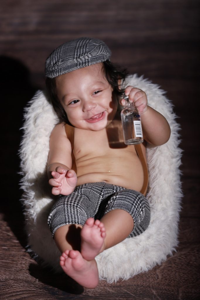 Baby Mavy doing a funny expression while holding a bottle for his newborn session